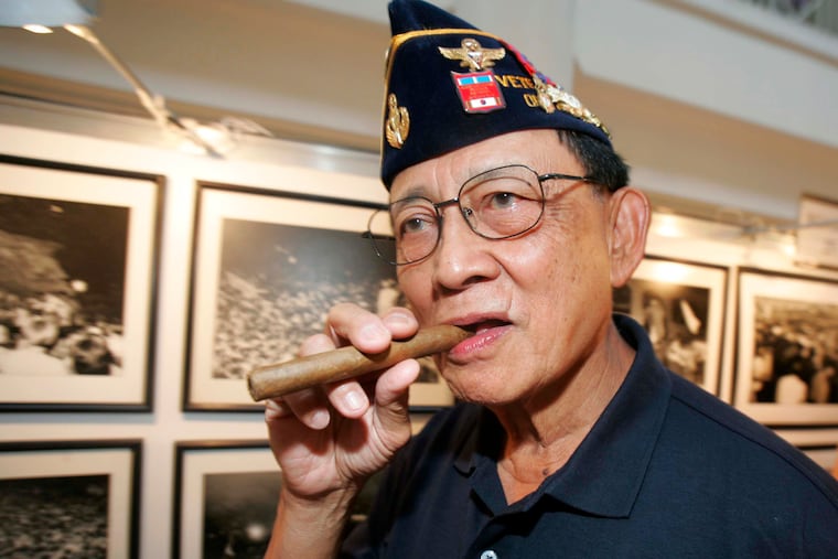 FILE - Former Philippine President Fidel Ramos bites his cigar as he looks on photographs during an exhibit on the 20th anniversary of "People Power" in suburban Makati, south of Manila, Philippines, on Feb. 22, 2006. Ramos, a U.S.-trained ex-general who saw action in the Korean and Vietnam wars and played a key role in a 1986 pro-democracy uprising that ousted a dictator, has died. He was 94. Some of Ramos's relatives were with him when he died on Sunday, July 31, 2022, said his longtime aide Norman Legaspi.