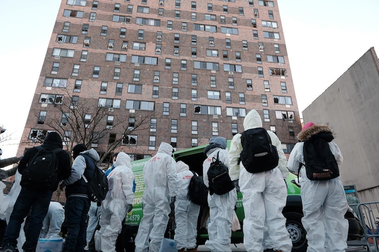 Clean-up and recovery workers gather in front of a Bronx apartment building a day after a fire swept through the complex killing 17 people and injuring dozens of others, many of them seriously, on Jan. 10, 2022, in New York City. (Spencer Platt/Getty Images/TNS)