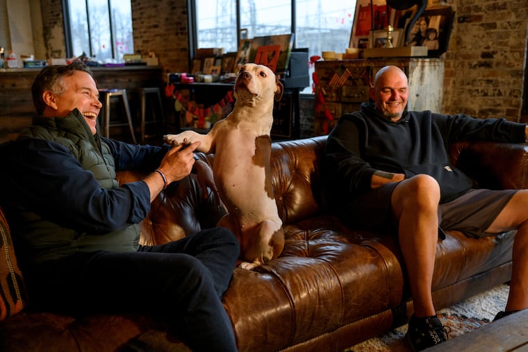 Pennsylvania Sens. Dave McCormick, left, and John Fetterman play with Fetterman's three-legged dog, Artie, at Fetterman's home in Braddock, Pennsylvania on Feb. 2. (Justin Merriman for The Washington Post)
