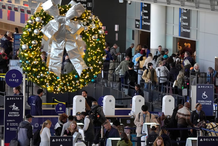 Travelers prepare to board aircraft near a holiday decoration on Monday, Nov. 25, 2024, at Boston Logan International Airport, in Boston.