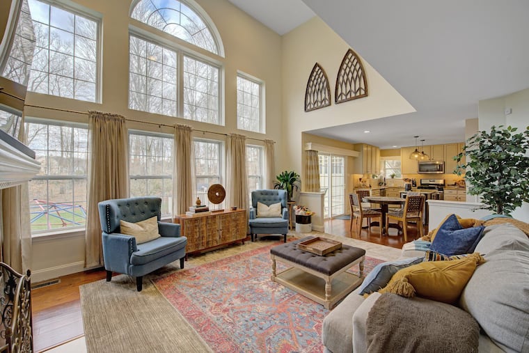The two-story family room has a gas fireplace and a wall of windows with views of the woods.