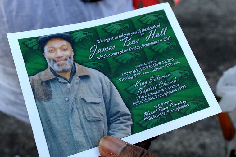 Friends and family of James "Bus" Hall pray for him and their neighborhood on York St. in the Fairhill section of Philadelphia. Here, a funeral card with Hall's photo on it. ( April Saul / Inquirer )