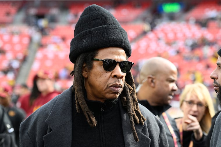 Jay-Z stands on the field before an NFL game between the Washington Commanders and Dallas Cowboys in November 2024, in Landover, Md. The rapper will headline the Roots picnic, backed by The Roots, on May 30 at the festival's new location on Belmont Plateau. (AP Photo/Nick Wass, File)