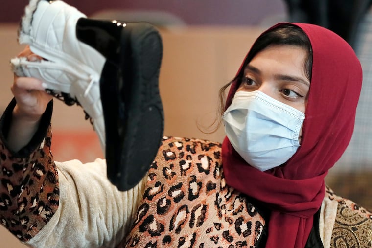 Sharifa Halimi of Philadelphia checks the size of donated winter boots at Imam Ali Masjid mosque in Pennsauken, N.J. last month. She helps lead a new Afghan-American organization that's working to help the Afghan evacuees now living on U.S. military bases.