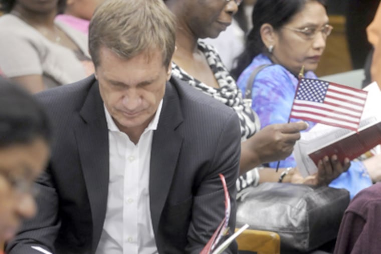Pierre Brondeau reads over his paperwork while waiting to be sworn in with other soon-to-be citizens. (Tom Gralish / Staff Photographer)