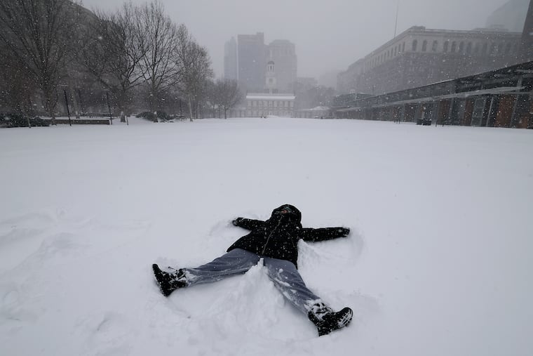 Julie Cohen makes a snow angel on the snow-covered lawn at Independence Mall on Sunday, Jan. 25, 2026.