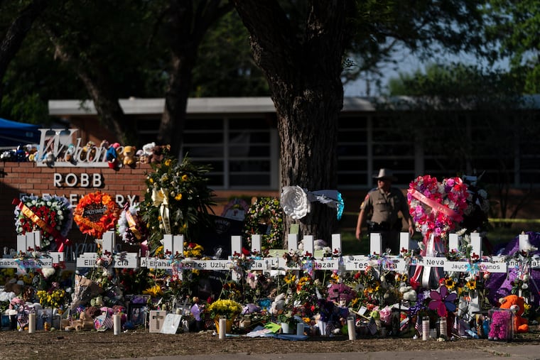 Flowers and candles are placed around crosses to honor the victims killed in a school shooting, May 28, 2022, outside Robb Elementary School in Uvalde, Texas.