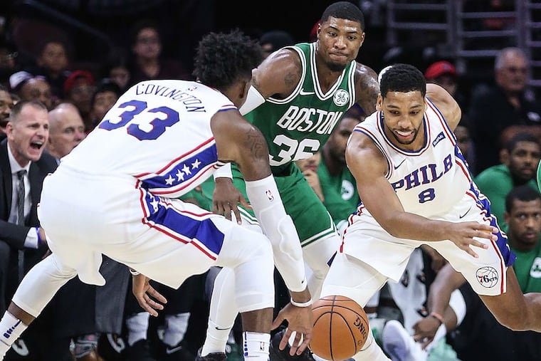 The Sixers’ Robert Covington and Jahlil Okafor try for a loose ball with the Celtics’ Marcus Smart.