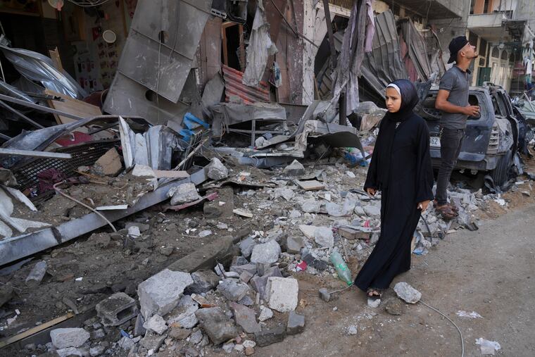 Palestinians walk by destruction by the Israeli bombardment of the Gaza Strip in the Maghazi refugee camp, in Deir Al-Balah on Wednesday.