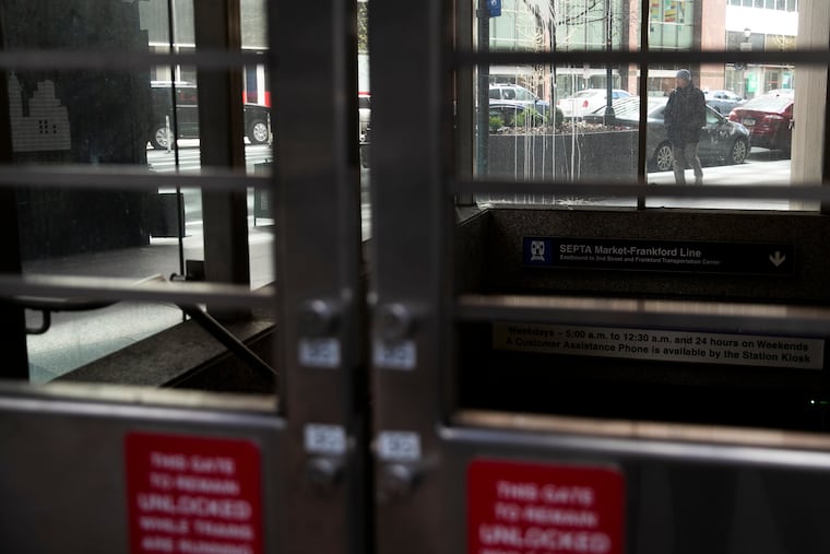 A man is seen walking behind a closed off SEPTA station at 15th and Market in Center City Philadelphia on Wednesday, April 22, 2020.