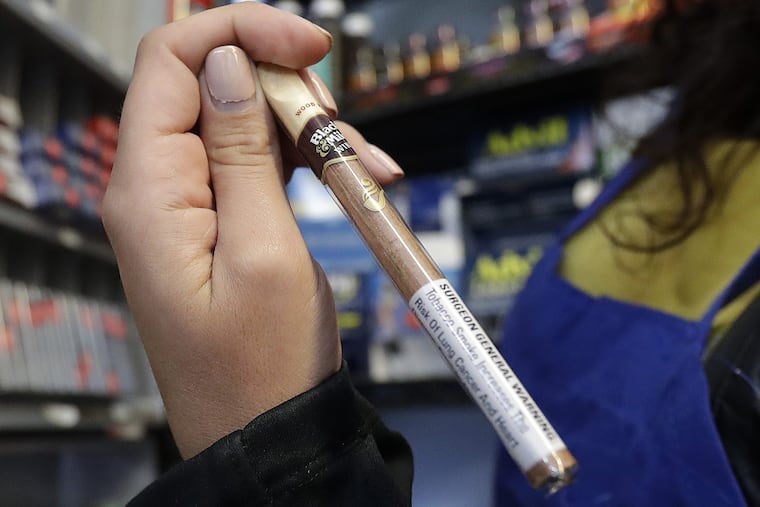 In this May 17, 2018 photo, Miriam Zouzounis holds a Black & Mild Wine cigarillo while interviewed at Ted's Market, her family's store, in San Francisco.