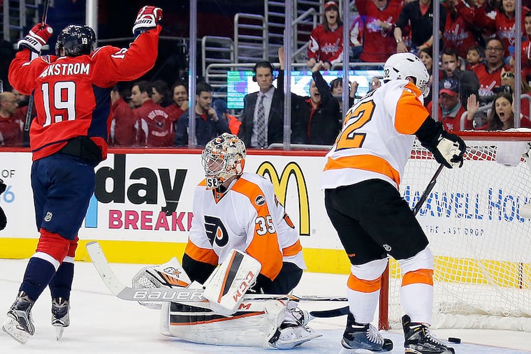 Flyers goalie Steve Mason sits on the ice with teammate Mark Streit
as the Capitals' Nicklas Backstrom celebrates teammates John
Carlson's goal.