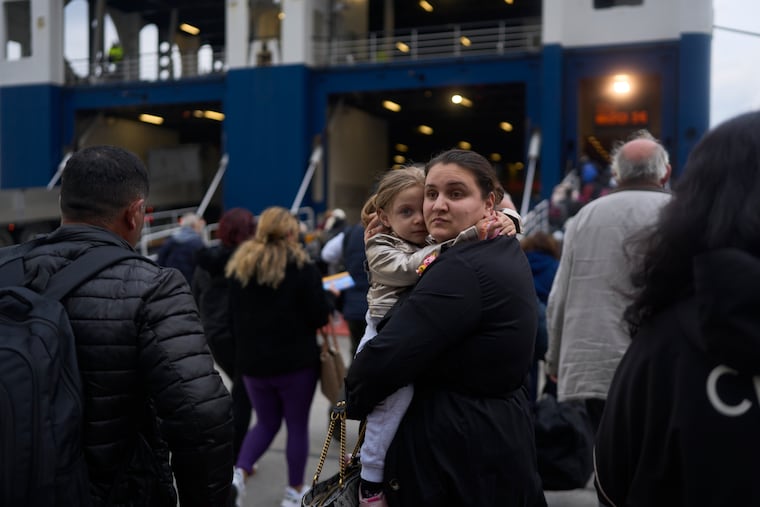 A woman with her child prepare to board a ferry bound for the Greek mainland on the earthquake-struck island of Santorini, Greece, on Tuesday, Feb. 4, 2025.