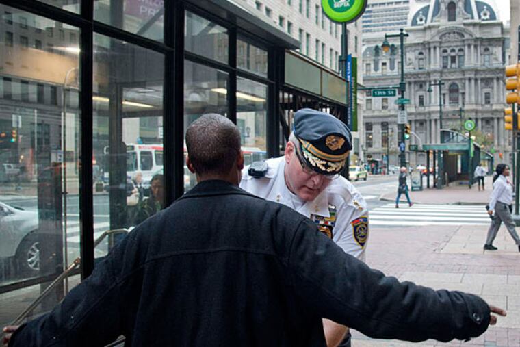 SEPTA Police Chief Tom Nestel frisks a man he suspected of selling tokens outside the entrance at the 12th Street station of the Market-Frankford El. (CLEM MURRAY / Staff Photographer)