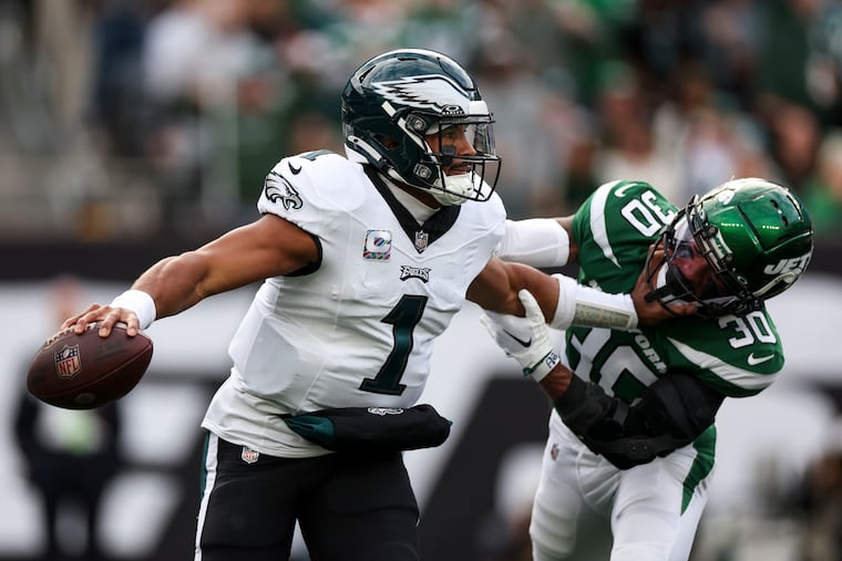 Eagles quarterback Jalen Hurts pushes off Jets cornerback Michael Carter II during the first quarter. Hurts threw three interceptions.