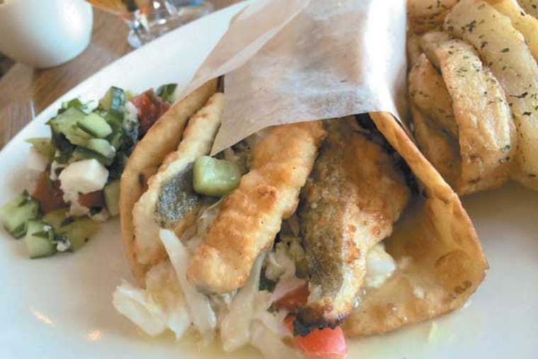 The "fish gyro" sandwich, a signature lunch item at the new Estia Taverna in Marlton (formerly Pietro's); it's made from pan-crisped halibut, finished with Greek yogurt, feta, slaw and relish of cucumbers, tomatoes and olives. (Craig LaBan / Staff)