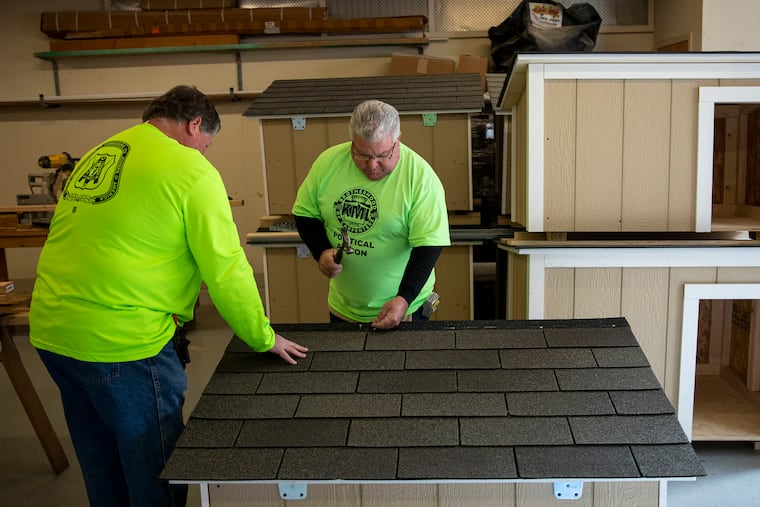 Retired union carpenters Ron Socha of Maple Shade, N.J., (left) and Tommy Jordan of Mount Laurel, N.J., finish roofing a doghouse at the Carpenters Union Hall, where they build customized doghouses and donate them to the Pennsylvania SPCA for free distribution to families in need.
