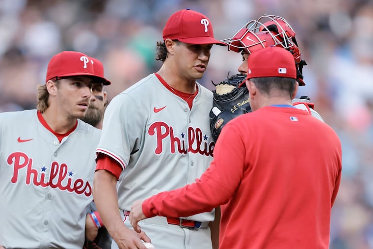 Starting pitcher Tyler Phillips, center, prepares to hand the ball to manager Rob Thomson, right, as he is relieved during the second inning after giving up a grand slam.