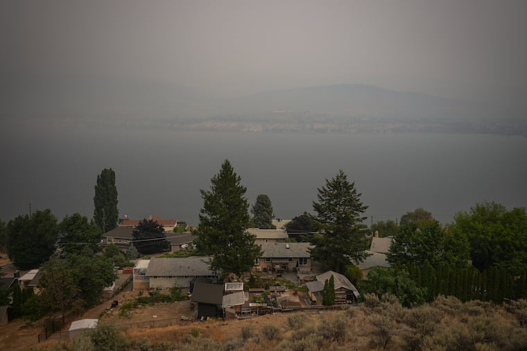 Houses overlooking Okanagan Lake are surrounded by smoke from the Bald Range wildfire blankets the area, in Penticton, British Columbia, Sunday, Aug. 9, 2026.