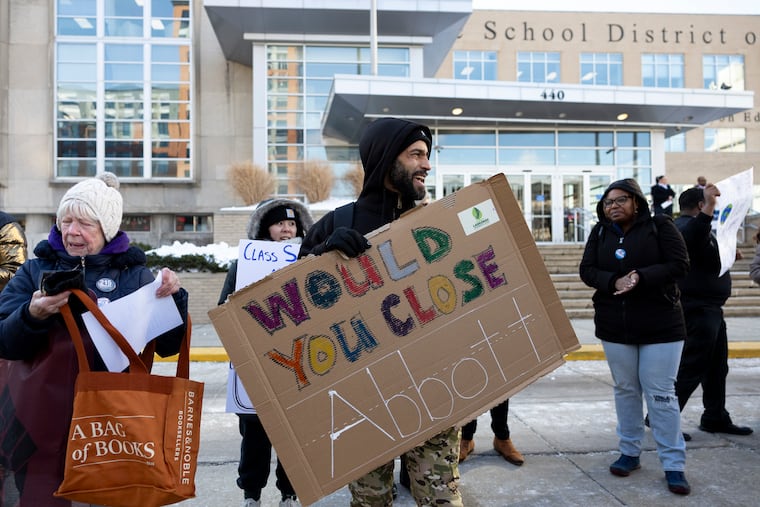 Jonathan Hoffmeier, 41, a teacher at Lankenau High School, holds a sign reading “Would you close Abbott” during a rally outside the School District of Philadelphia on Thursday.