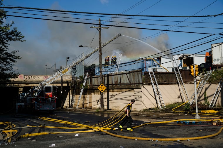 Authorities work to extinguish a stubborn junkyard fire in the Kensington neighborhood of Philadelphia, Wednesday, July 11, 2018. The fire was reported around 8:30 p.m. Tuesday and spewed thick smoke and flames that could be seen for miles. Authorities say the burning materials consisted mainly of metal, wood, and paper.