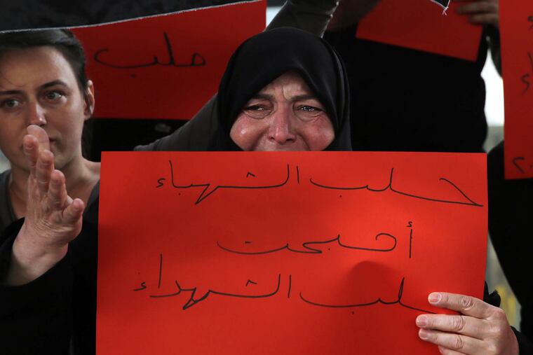 A Syrian woman weeps as she holds a placard that reads "Aleppo has become the Aleppo of martyrs" during a protest against Syrian President Bashar Assad's military operations against areas held by insurgents in the northern city of Aleppo.