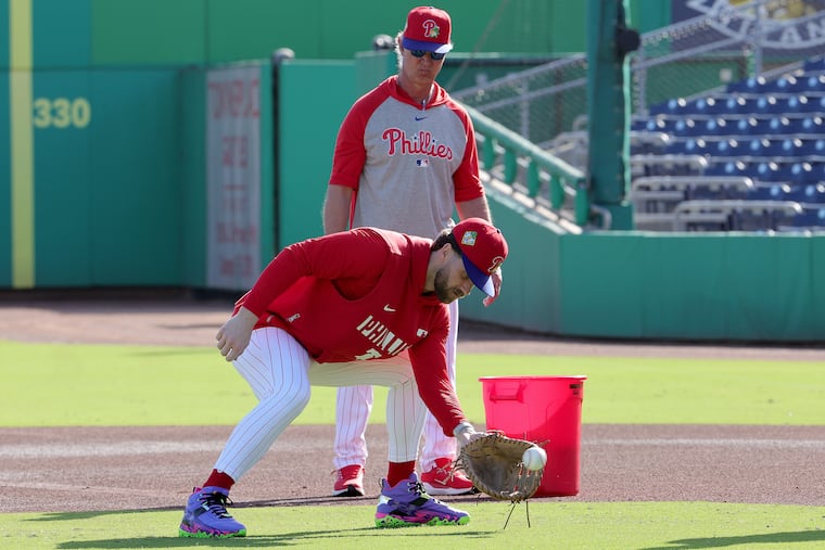 Phillies bench coach Don Mattingly watches as Bryce Harper fields ground balls in his new "Mad House" cleats from Under Armour.