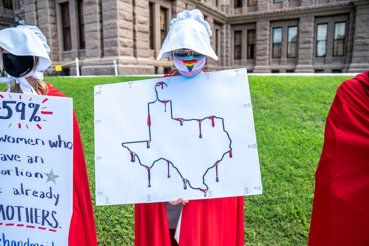 A protester dressed as a handmaiden holds up a sign at a protest outside the Texas state capitol on May 29, 2021, in Austin, Texas. (Sergio Flores/Getty Images/TNS)