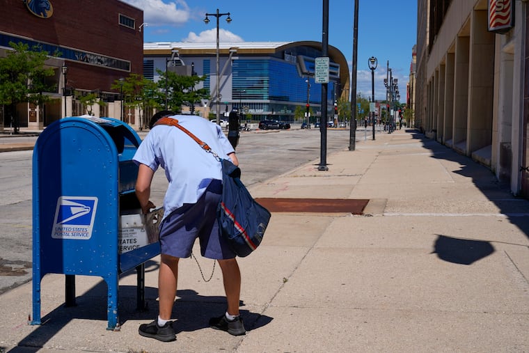 A postal worker empties a box near the Fiserv Forum in 2020 in Milwaukee.