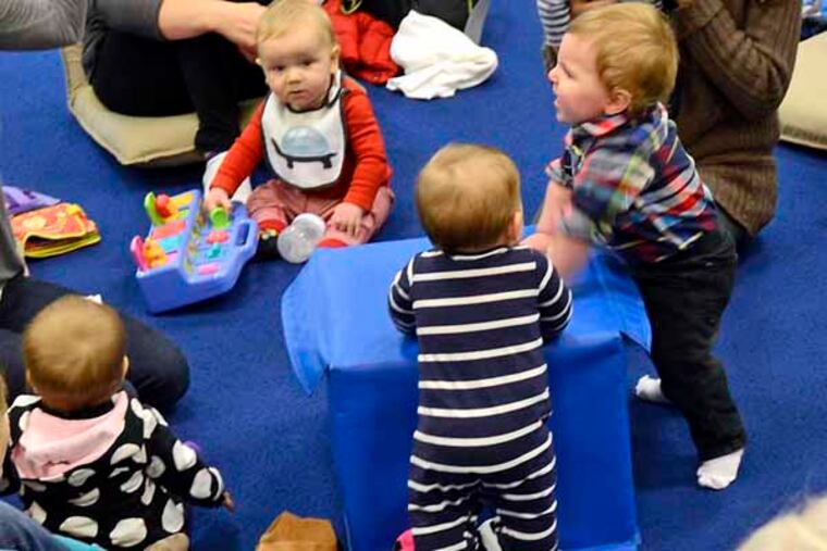 Child development/parenting education specialist Joanie Nolen (front, back to camera) conducts her weekly education and support group for first time parents at NEST December 26, 2013. NEST, which opened in August 2011, was the first membership-based all-inclusive children's boutique and play area/birthday party area/parenting center in the city. The mothers, clockwise from left are: Rebecca Franco, with William, 8 mos; Amie Koch, with Stella, 9 mos; Lauren Krigel, with Lillian, 9 mos; Liz Morello, with Ben, 7 mos; Zoe Weinstein, with Harrrison, 8 mos; Rececca Oller, with Max Rodner, 10 mos; Renay Shaw, with Sophia, 8 mos; and Stefanie Schoenberger, with Chloe, 11 mos. (they're all from Center City, kid's last name the same as mom, except as noted). ( TOM GRALISH / Staff Photographer )
