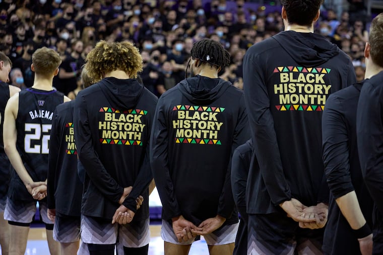 Washington players stand during the playing of the national anthem wearing warm-up jackets for Black History Month before an NCAA college basketball game against Arizona, Feb. 12, 2022, in Seattle.