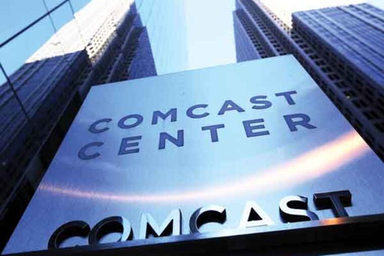 FILE - In this Dec. 3, 2009 file photo, a sign outside the Comcast Center, left, is shown in Philadelphia. Comcast Corp. reported an 8 percent drop in third-quarter earnings Wednesday, Oct. 27, 2010, a decline caused by expenses related to its pending acquisition of NBC Universal and other one-time costs.(AP Photo/Matt Rourke, file)