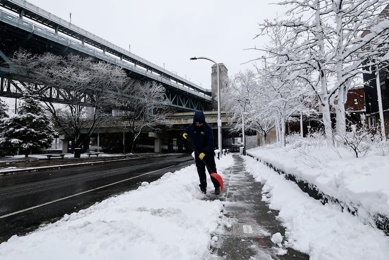 Sean Little of the Delaware River Waterfront Corporation shovels snow along the sidewalks on Race Street on Monday.