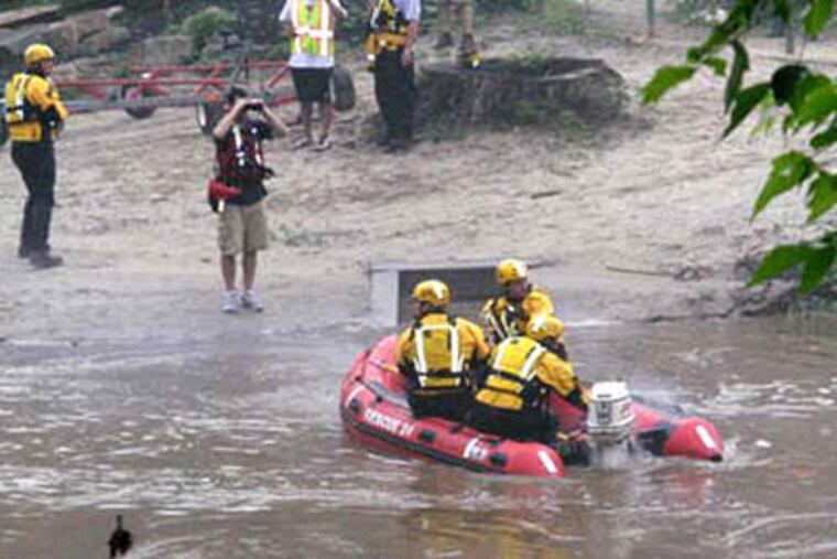 Rescue workers search Brandywine Creek for a missing kayaker in East Bradford Township. Another kayaker was pulled from the swollen creek, but died. (Kathleen Brady Shea / Staff)