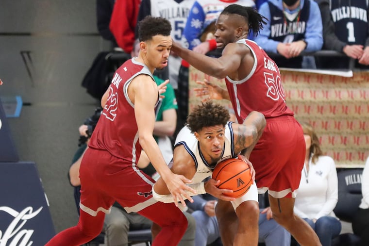 Villanova Wildcats guard Justin Moore (5) is surrounded by Saint Joseph's Hawks guard Jordan Hall (22) and Saint Joseph's Hawks forward Ejike Obinna (50) as he looks to pass the ball in the second half of a game at the Finneran Pavilion on Saturday, Dec. 4, 2021. Villanova won, 81-52.
