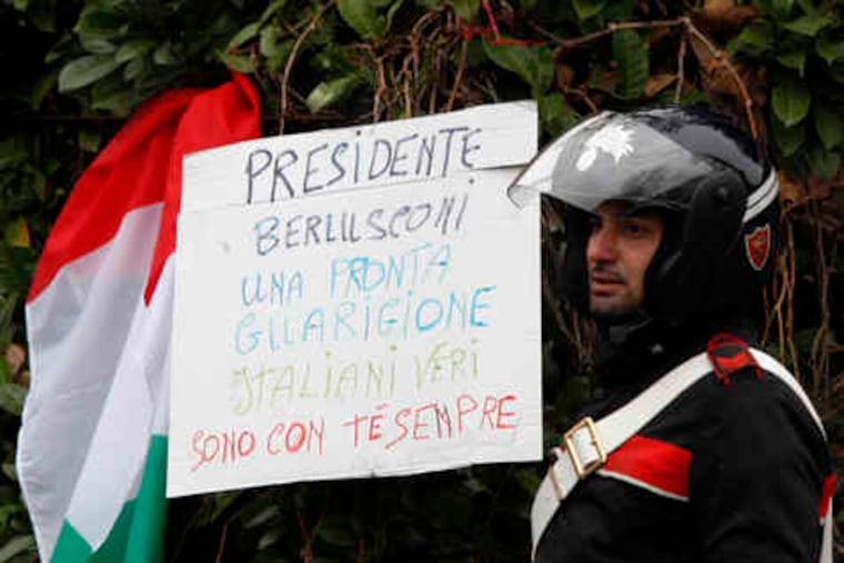 Outside Milan's San Raffaele Hospital , a paramilitary police officer is flanked by a sign, next to an Italian flag, that reads: "President Berlusconi, get well soon. Real Italians are with you always."