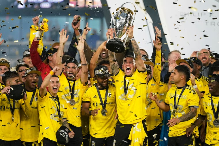 Columbus Crew players celebrate as Christian Ramírez holds up the MLS Cup trophy.
