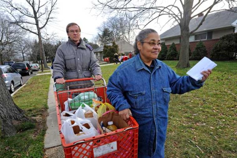 At the Cherry Hill food pantry, folks receive food on Dec. 20, 2012. Here, Carmen Pierce gets a helping hand from volunteer Rich Burke. APRIL SAUL / Staff Photographer