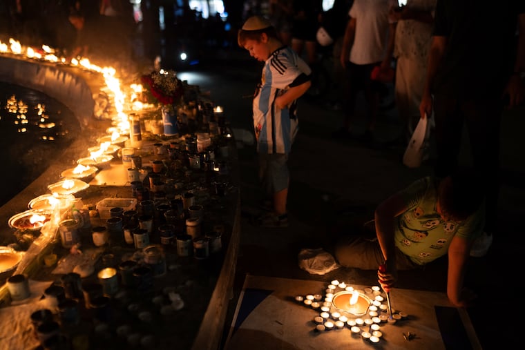 A boy lights candles in the form of the Star of David in honor of victims of the Hamas attacks during a vigil at the Dizengoff square in central Tel Aviv, Israel, Wednesday, Oct 18, 2023.