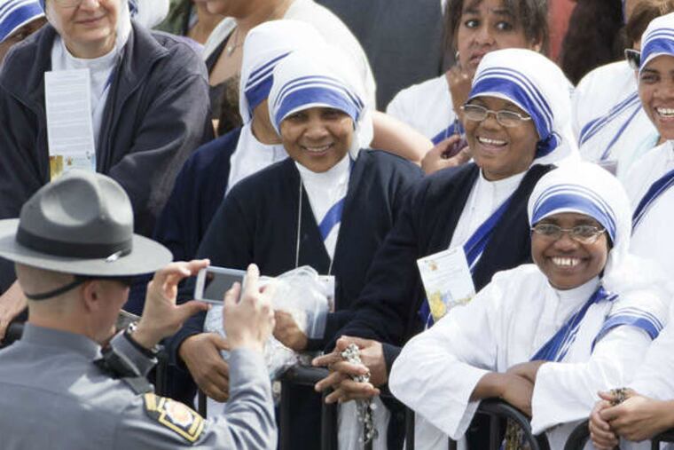 A state trooper takes a break from his official duties to take a photo of a group of pilgrims at Independence Mall.(Ed Hille / Staff Photographer)