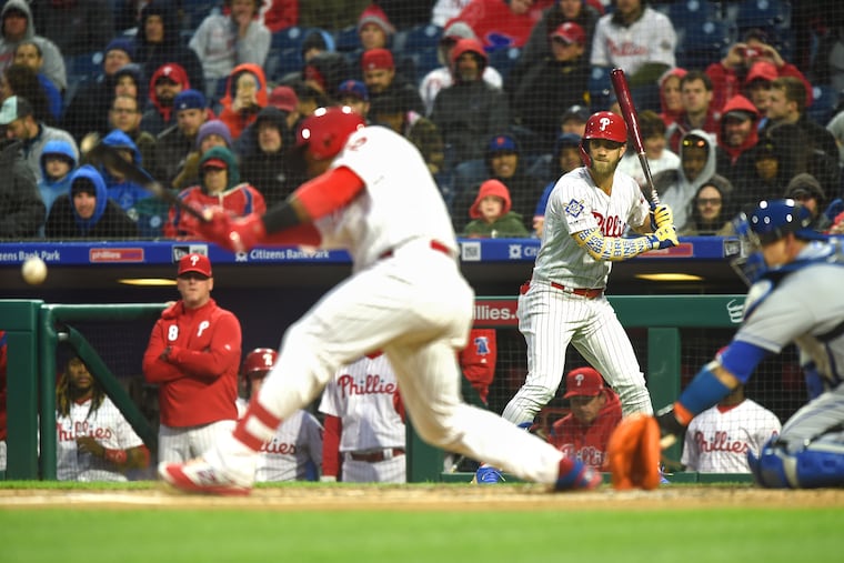 Bryce Harper (rear) watches from the on-deck circle as Jean Segua singles in the first inning of the Phillies' 7-6 loss to the Mets on Monday. The game went to 11 innings.