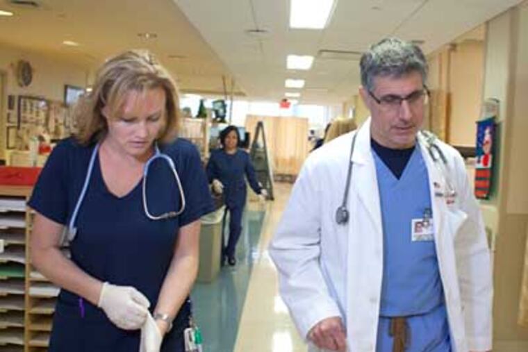 Dr. Alfred Sacchetti and nurse Erica Frampton work in the ER at Our Lady of Lourdes Medical Center in Camden, where procedures have been changed to improve patient flow. (ED HILLE / Staff Photographer)