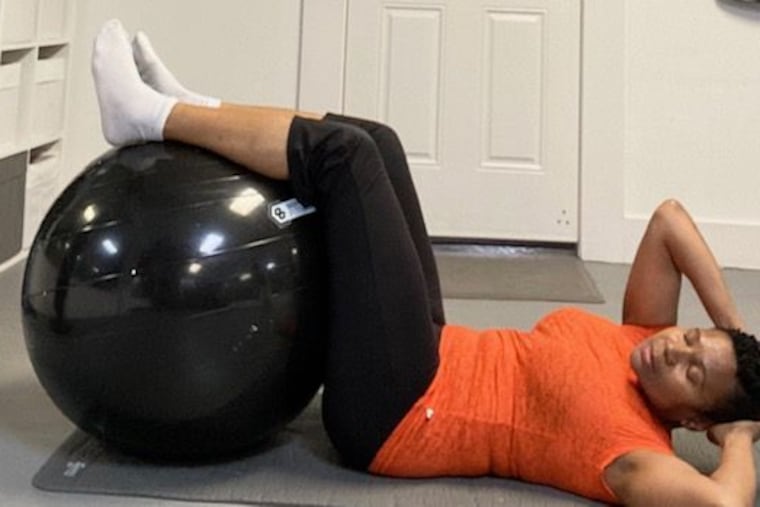 Demonstrating beginner floor crunches and a twist with a stability ball.
