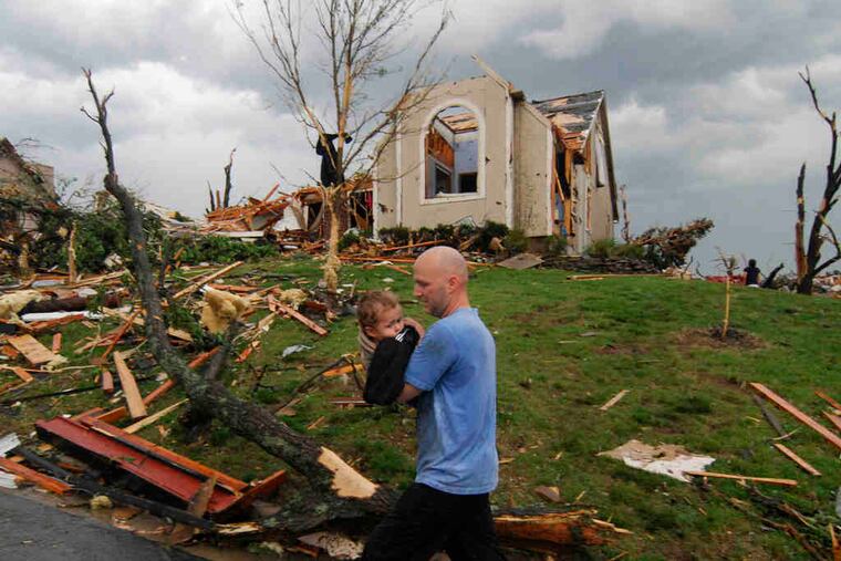 A man carries a young boy rescued after being trapped in his home in Joplin, Mo. The tornado, at times three-quarters of a mile wide, did some of its most startling damage at St. John's Regional Medical Center, where five patients and one visitor died.