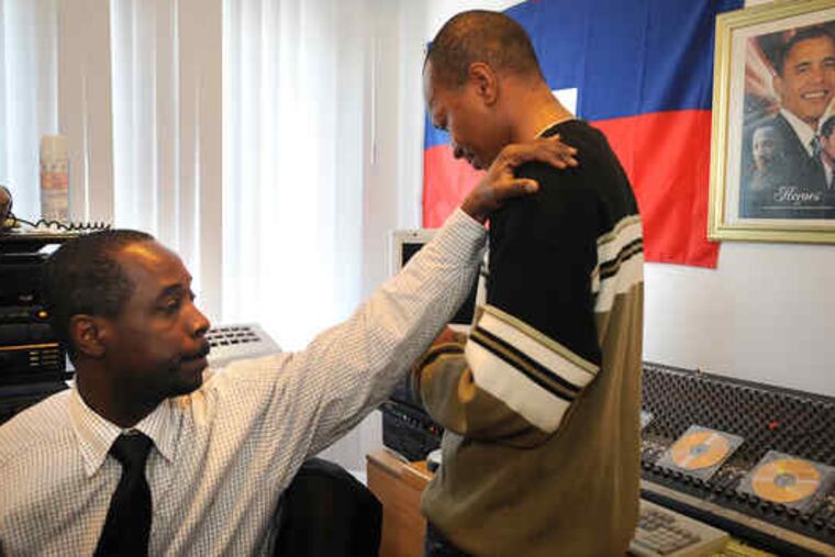 At Radio Vision Celeste in Northeast Philadelphia, commentator Jean Renel Boucher comforts station news director Fritz Momperousse, who awaits news about his family in Haiti. Yesterday, Boucher fielded calls from the reeling local Haitian community. He learned his son, 12, had survived.