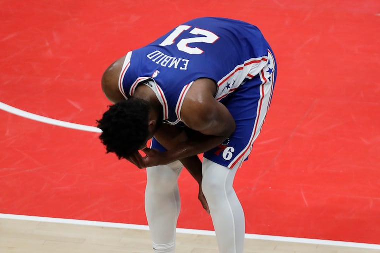Sixers center Joel Embiid leans over after falling down while driving to the basket during the first quarter against the Washington Wizards in Game 4.