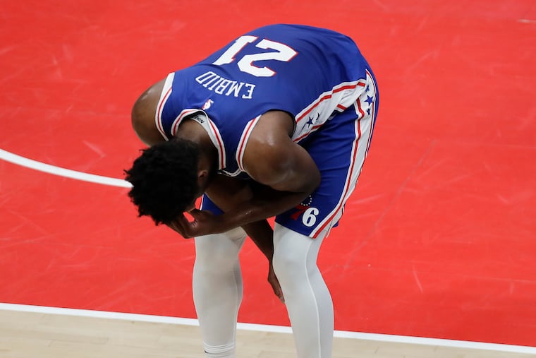 Sixers center Joel Embiid leans forward after falling down driving to the basket during the first quarter against the Washington Wizards in Game 4 Monday night.