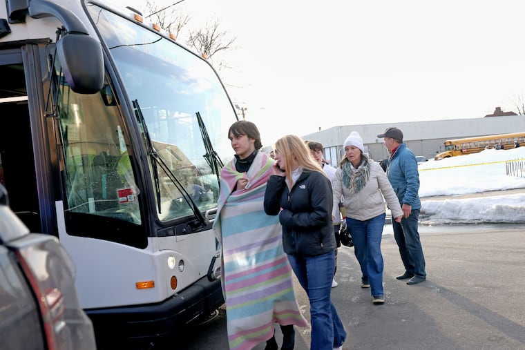 High school hockey students walk onto a public transit bus near the Lynch Arena in Pawtucket, R.I., after a shooting at the ice rink on Monday, Feb. 16.