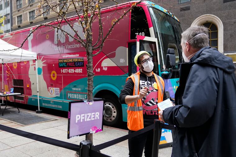 A health-care worker (left) checks in a man at a New York City mobile vaccine clinic in Midtown Manhattan on Monday.