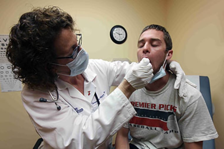 Nurse practitioner Teresa Long of the Take Care Clinic in Wilmington, Del., attends to a patient who came in with flu-like symptoms. (Suchat Pederson/AP/The News-Journal)